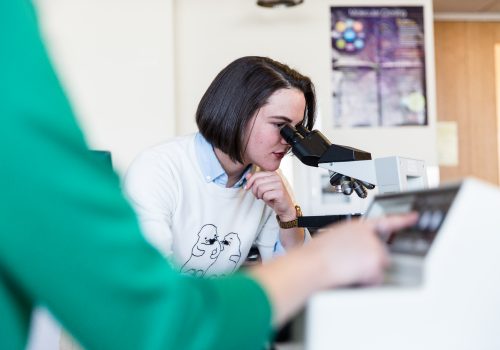 Student in the lab looking through a microscope